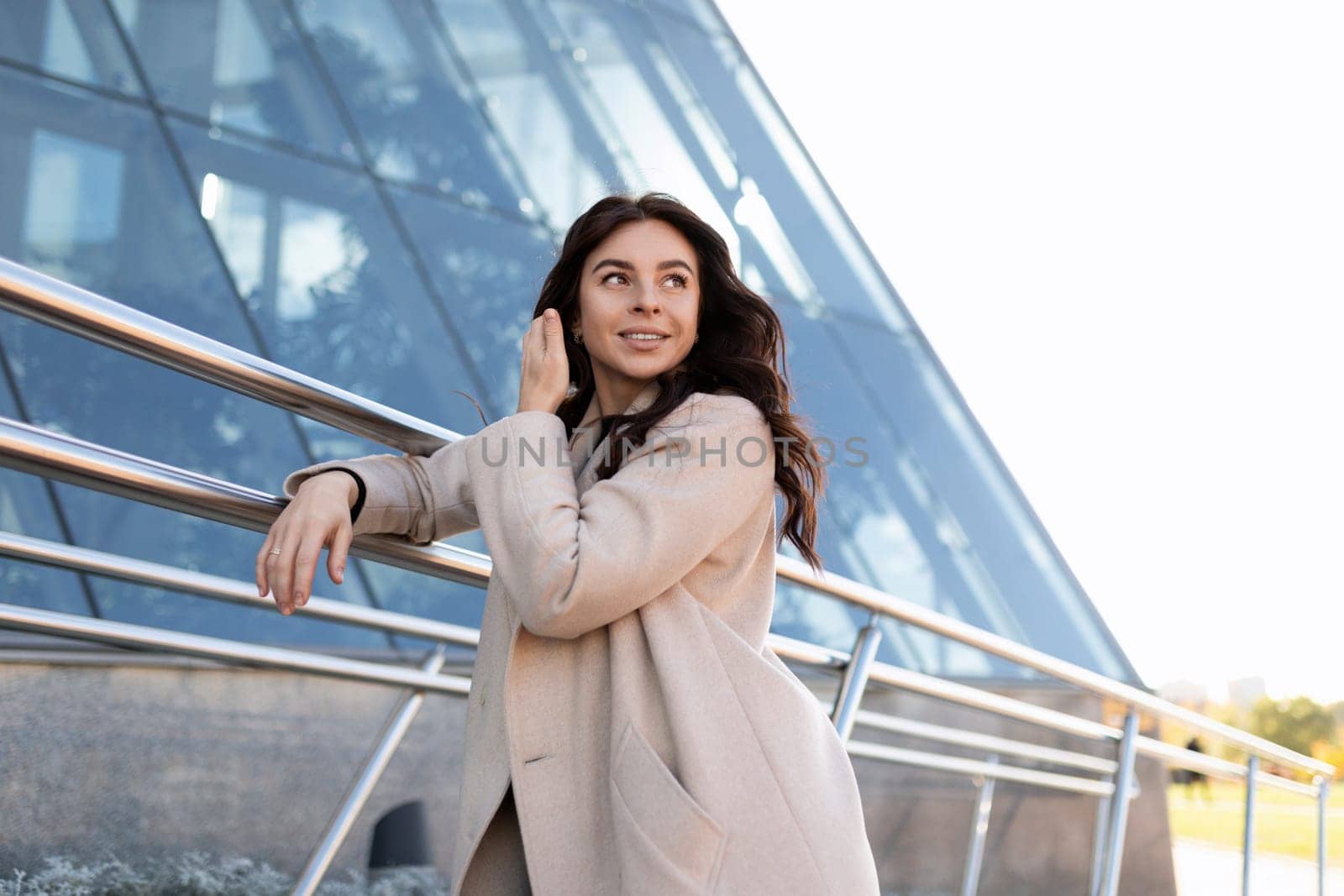 successful business woman in a coat on the background of the glass facade of an office building.