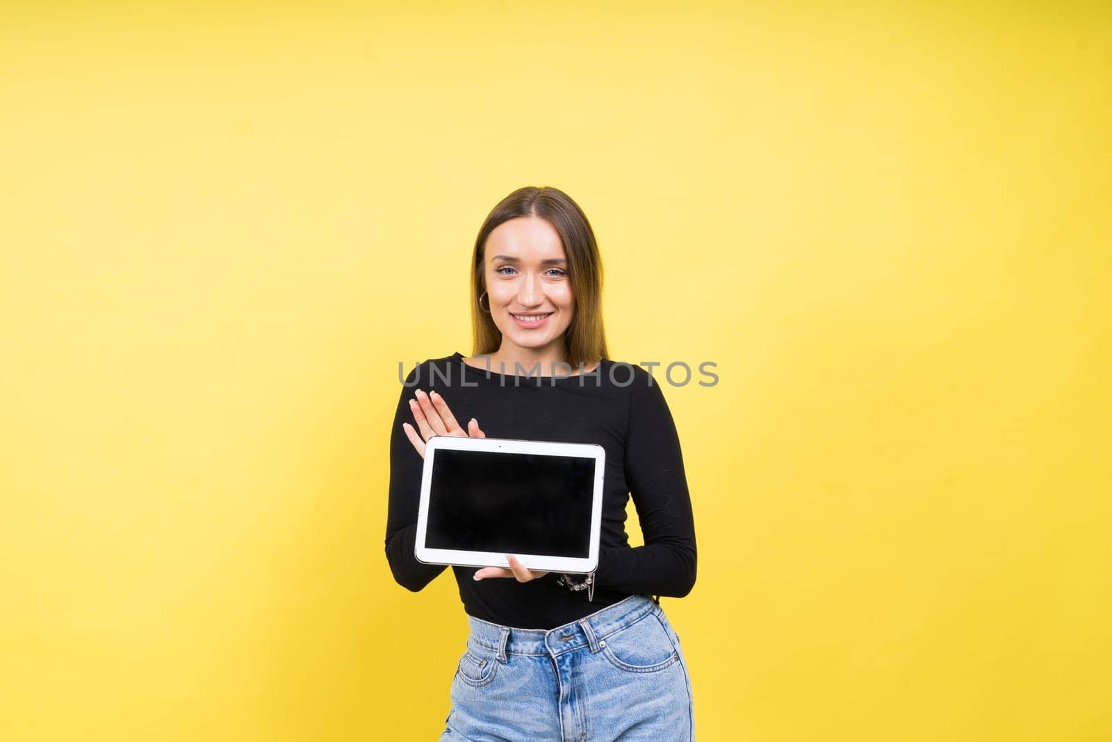 Smart intelligent caucasian young woman student using digital tablet isolated over yellow background by Zelenin