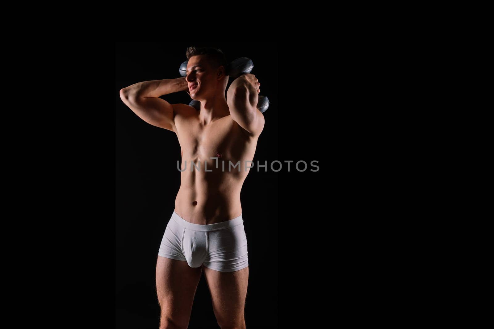 Shirtless bodybuilder holding dumbell and showing his muscular arms. by Zelenin