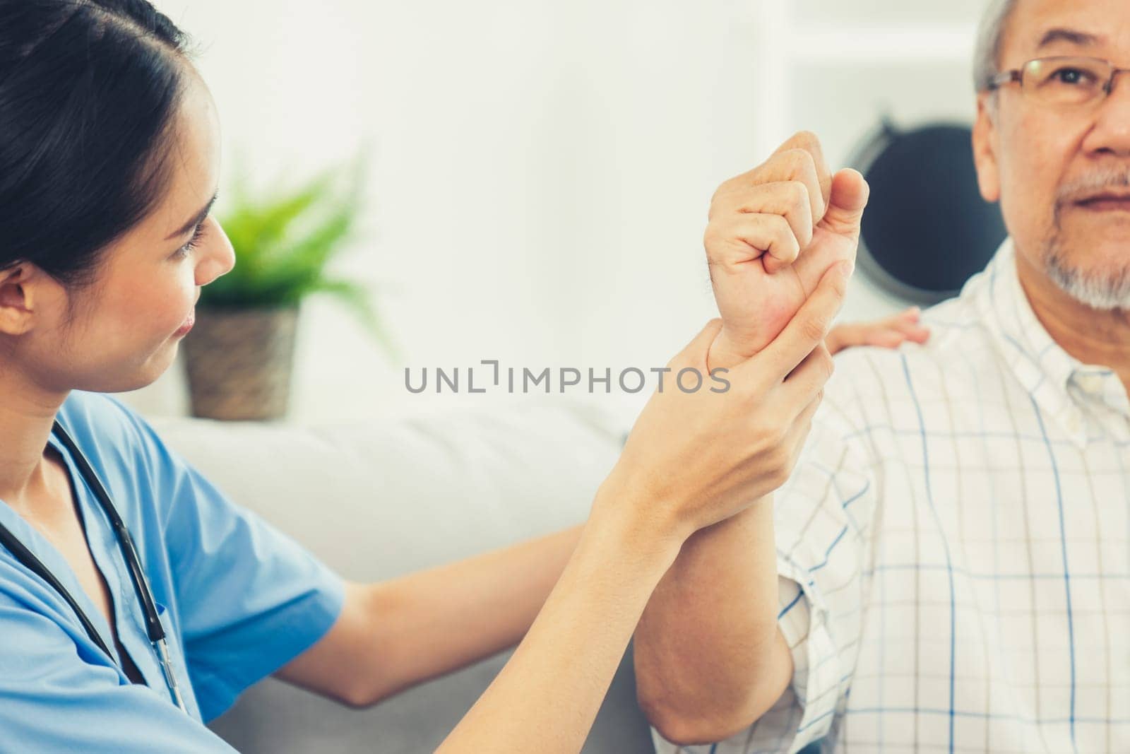 Caring young female doctor performing osteopathy treatment for a contented senior patient. At-home medical treatment for an Asian senior patient, joint pain treatment, medical service for seniors.