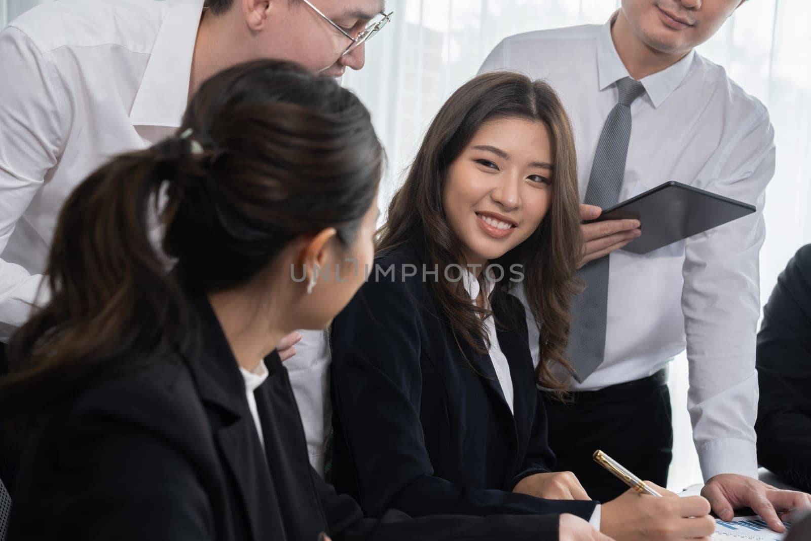 Engaging businesspeople working at desk together as concept of harmony in office by biancoblue