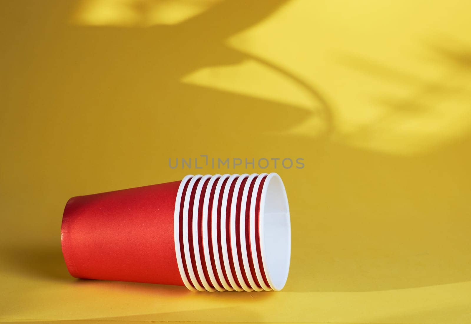 bright red disposable cups on a yellow background disposable tableware by Севостьянов