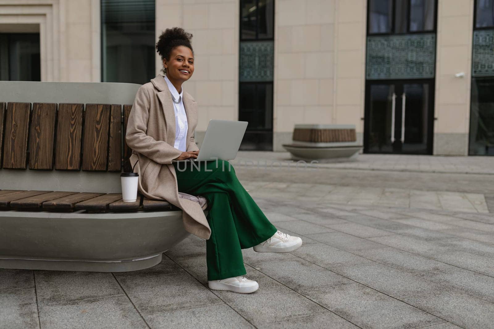 middle aged african american woman working on laptop outside.