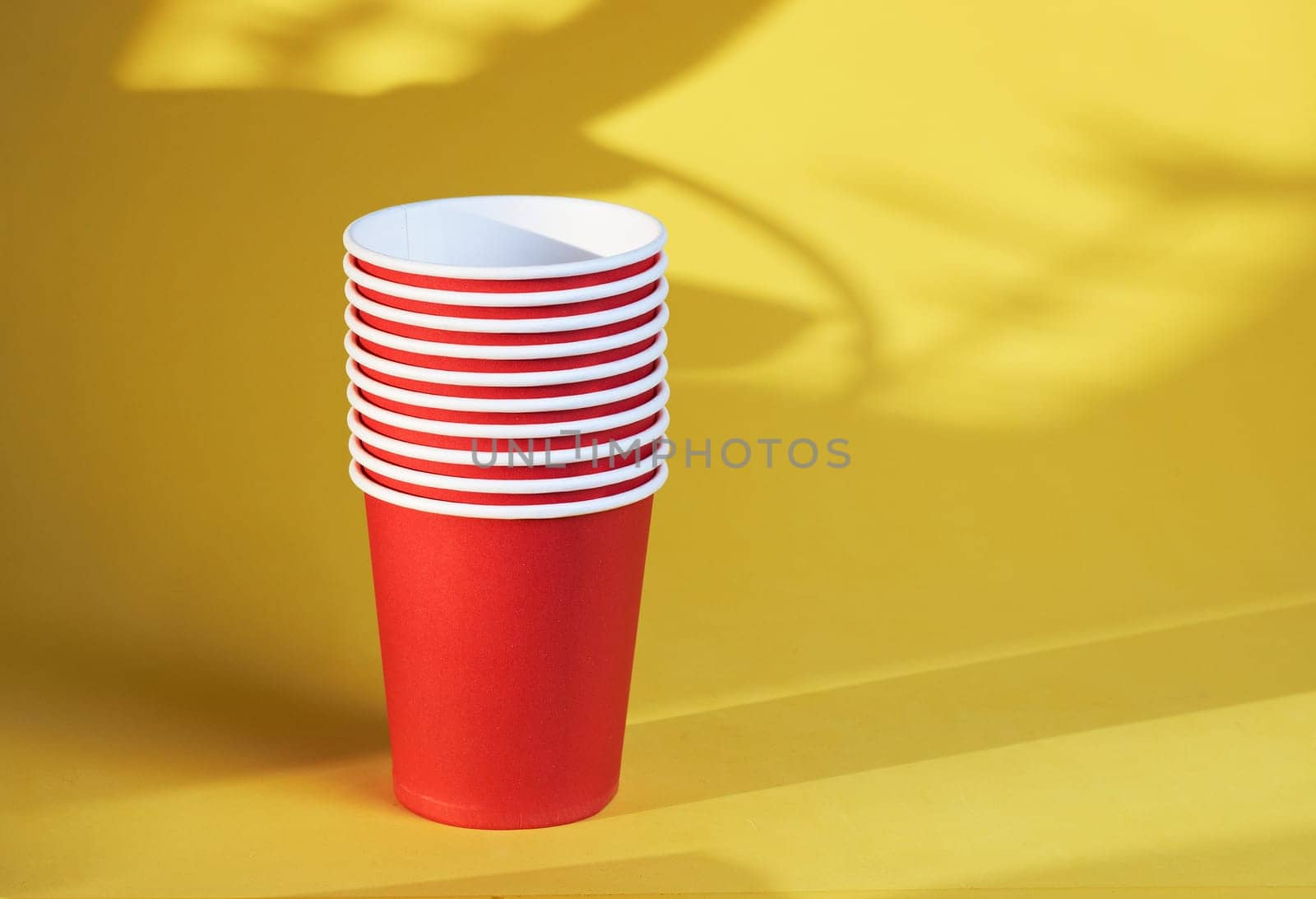 bright red disposable cups on a yellow background disposable tableware by Севостьянов