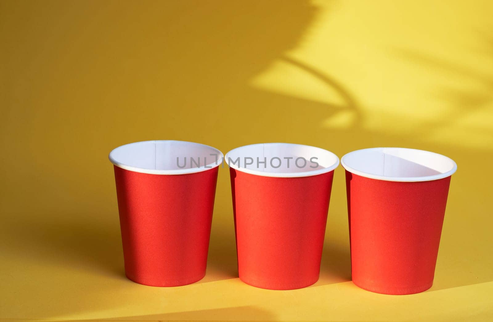 three red paper coffee cups on a yellow background is a morning concept