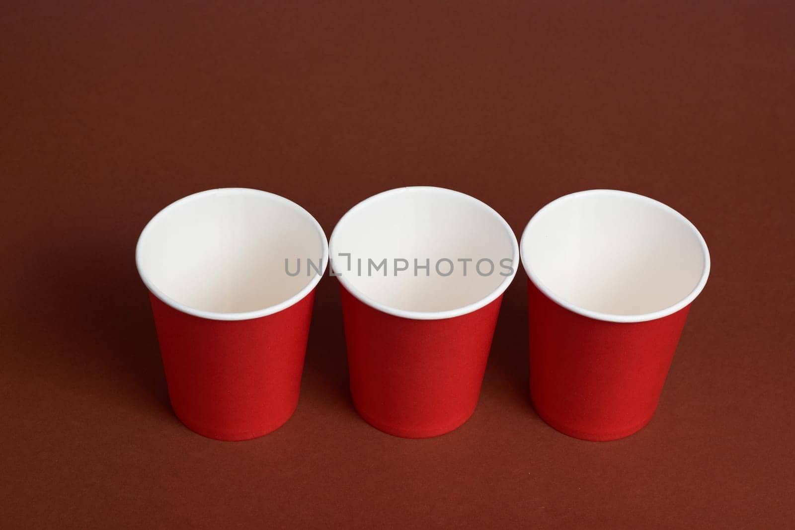 three red paper coffee cups on a dark brown background. Morning concept.
