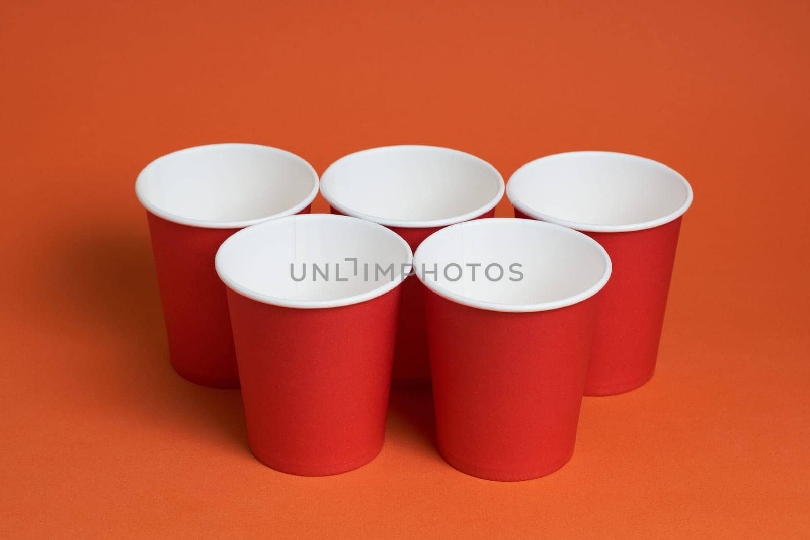 Five red disposable cups on a brown background. Place for text by Севостьянов