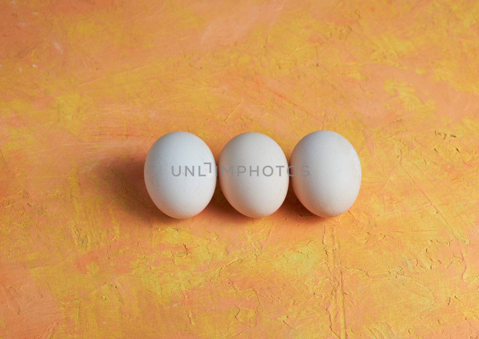 Three Easter white eggs on a yellow background by Севостьянов