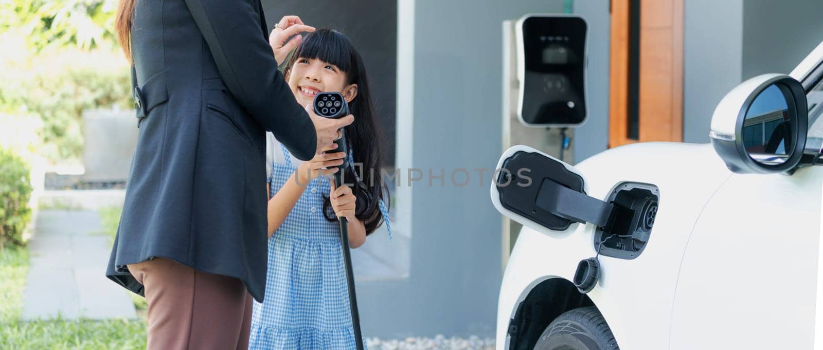 Progressive lifestyle of mother and daughter with EV car and charging station. by biancoblue