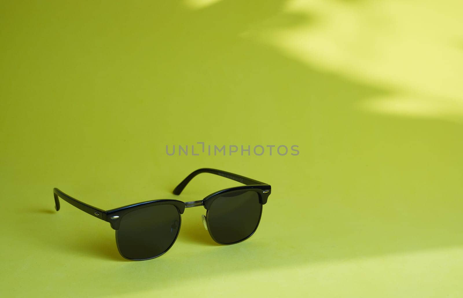 Black glasses on a light green background. Side view. Place for text.