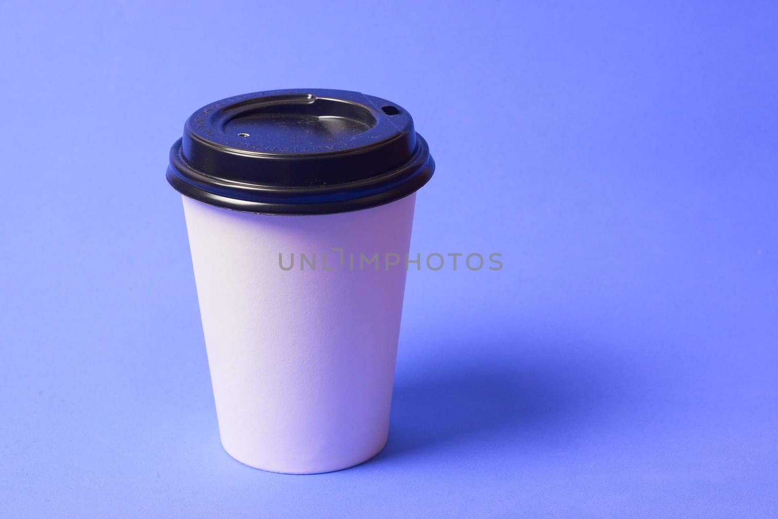 Paper coffee container with a black lid and on a blue background a white coffee paper cup with a black lid takeaway coffee