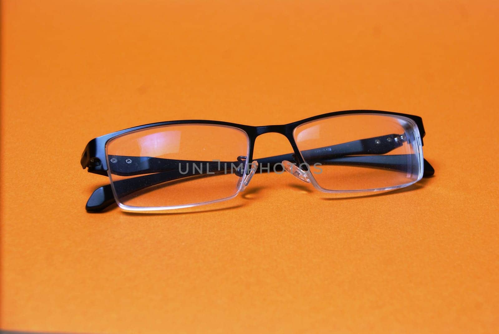 The glasses are on a bright orange background close-up