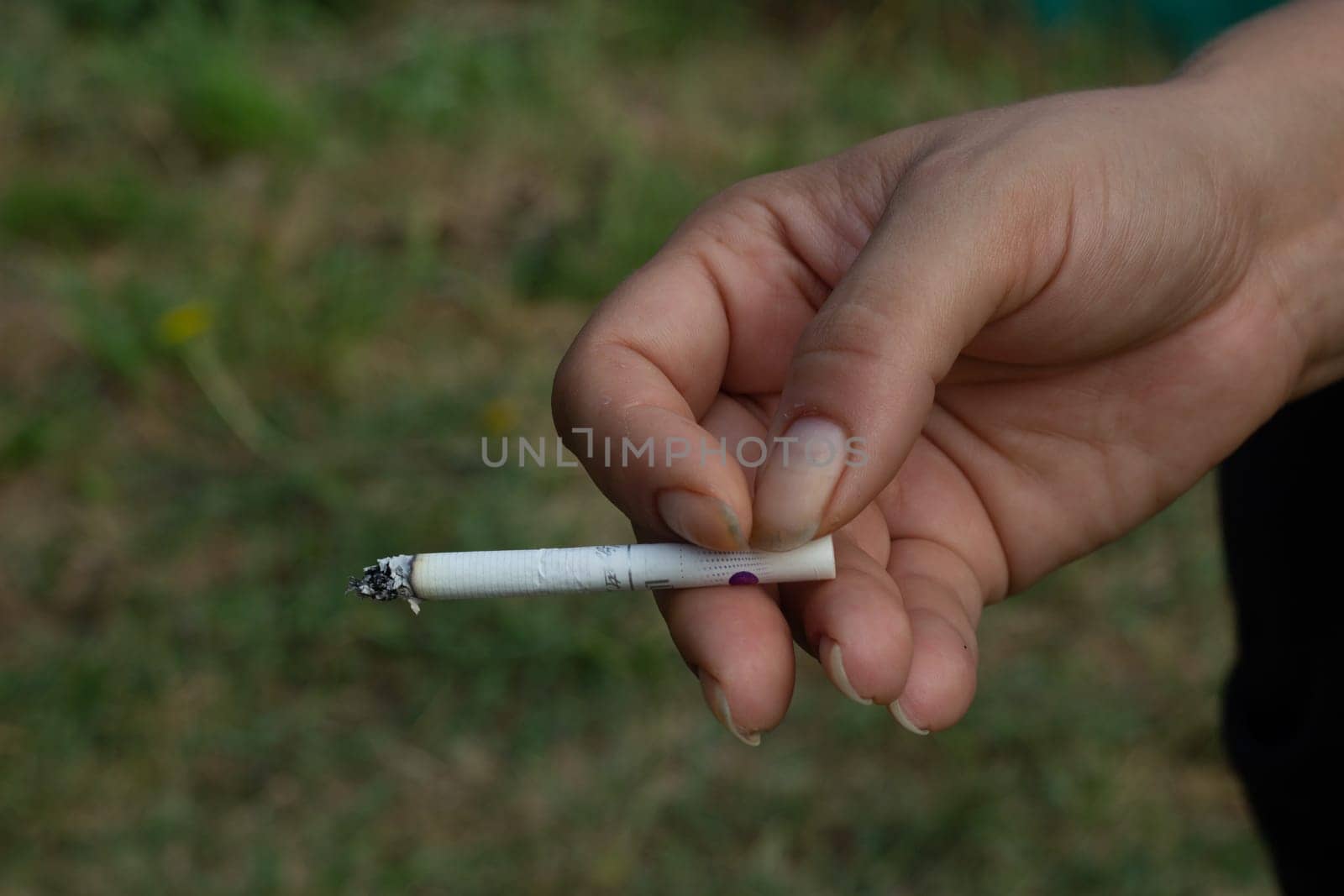 A woman hand is holding a cigarette street by electrovenik