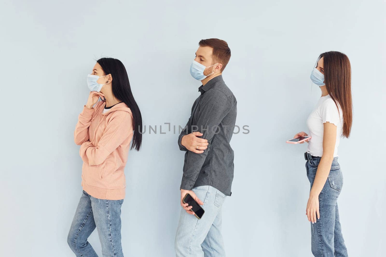 Three people standing together in the studio against white background by Standret