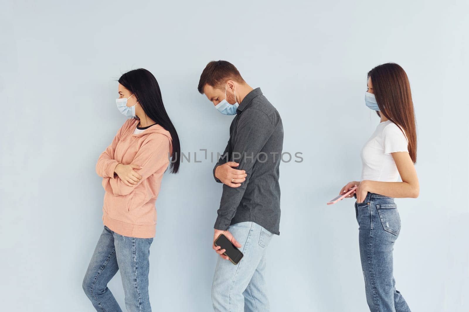 Three people standing together in the studio against white background by Standret