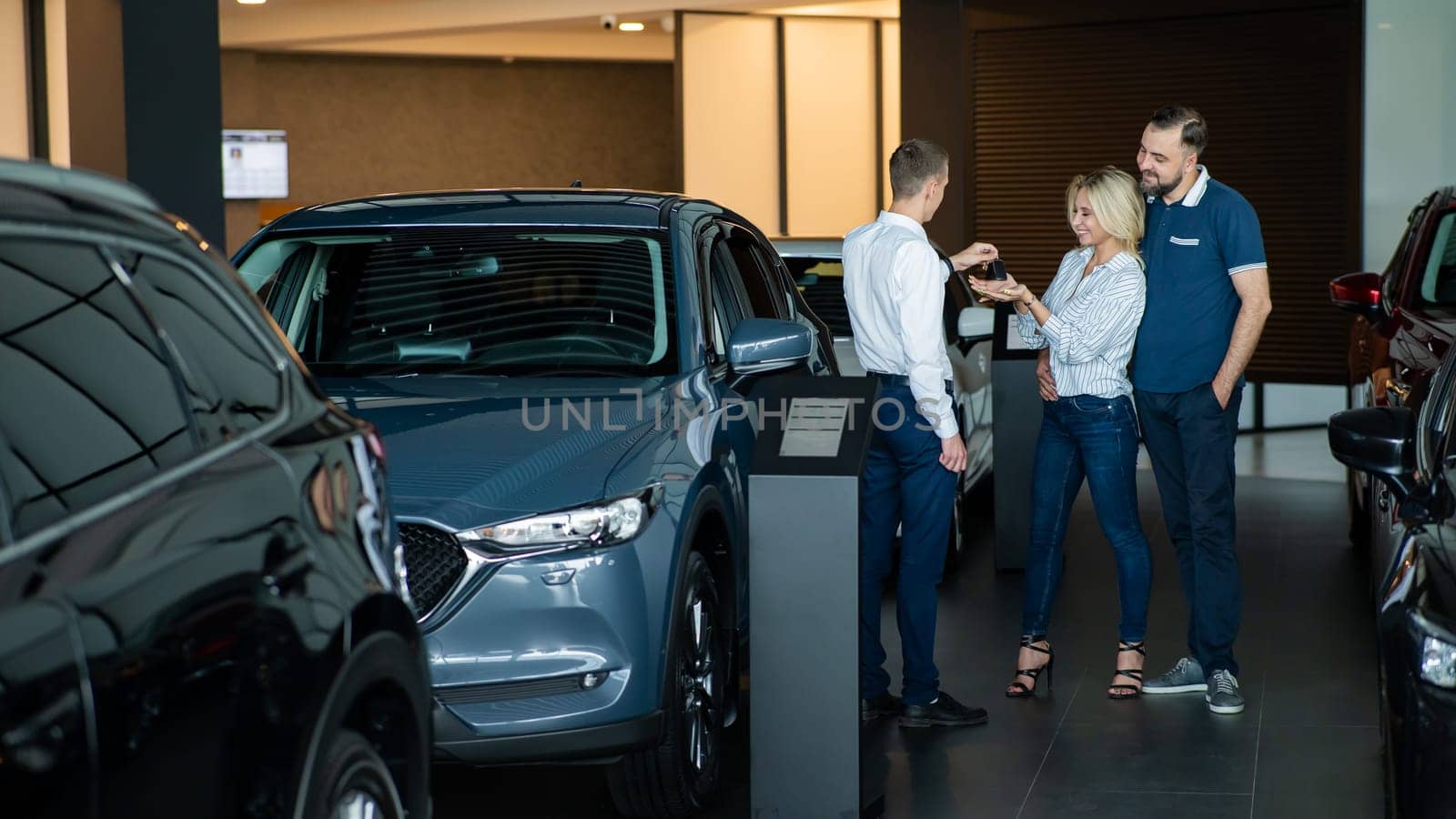 The seller hands over the car keys to the buyers. The couple bought a new car
