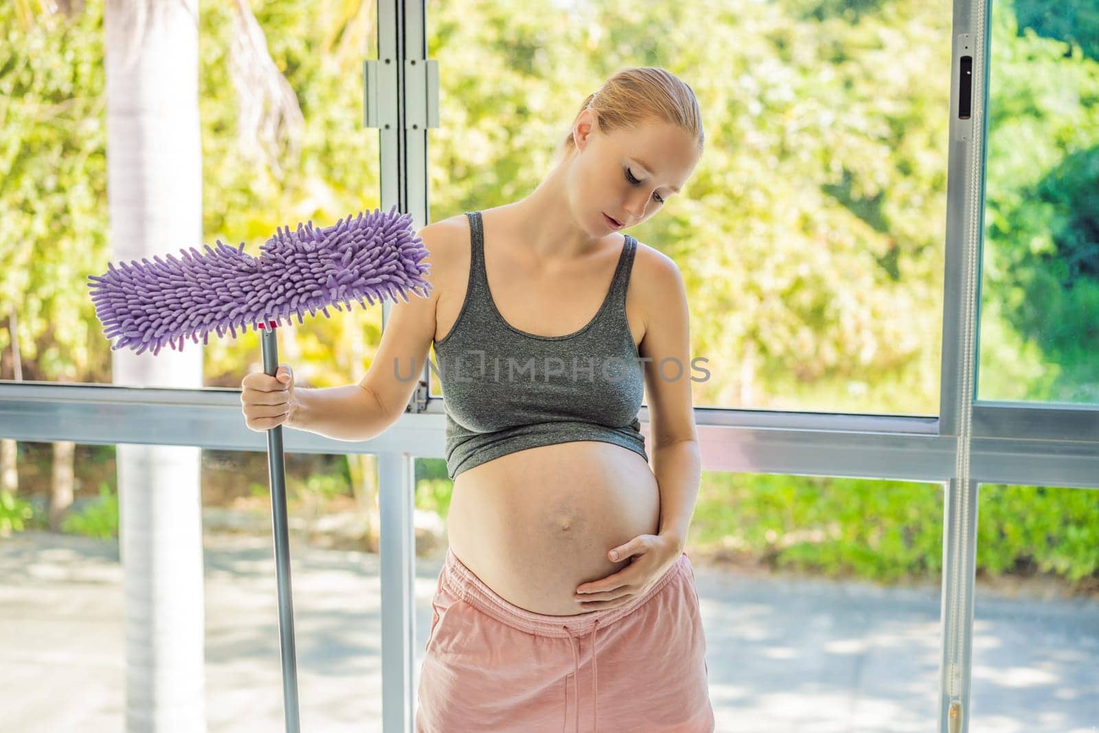 Pregnant woman washes the floor and is tired. Tired pregnant woman having pain in back while she is cleaning her house.