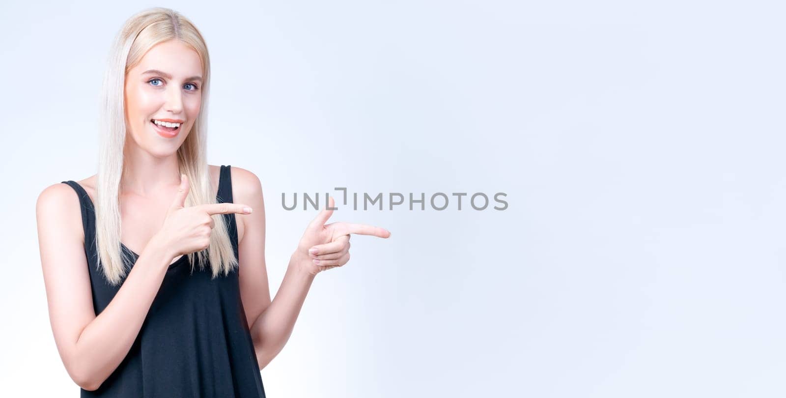 Personable woman pointing finger advertising product in isolated background. by biancoblue