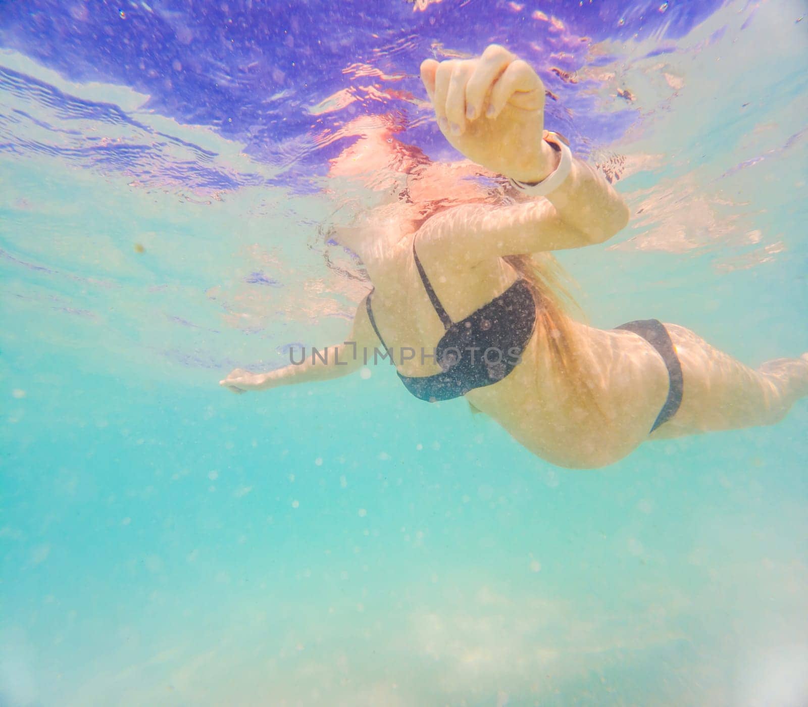 Pregnant woman underwater swimming in tropical sea. Healthy and active pregnancy. Young expecting mom on summer beach vacation before baby birth. Swim holiday and water fun. Travel during pregnancy. Underwater photography.