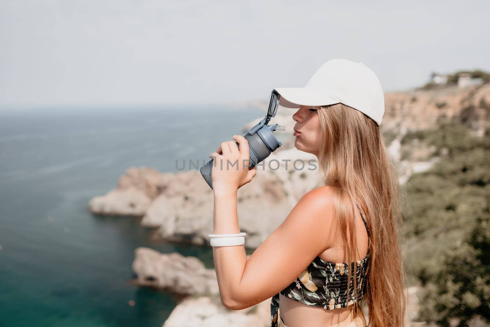 Woman travel sea. Happy tourist taking picture outdoors for memories. Woman traveler looks at the edge of the cliff on the sea bay of mountains, sharing travel adventure journey.