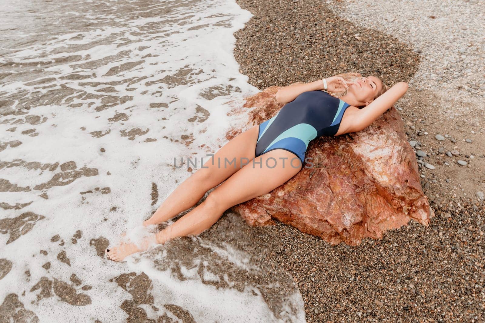 Woman travel sea. Young Happy woman in a long red dress posing on a beach near the sea on background of volcanic rocks, like in Iceland, sharing travel adventure journey