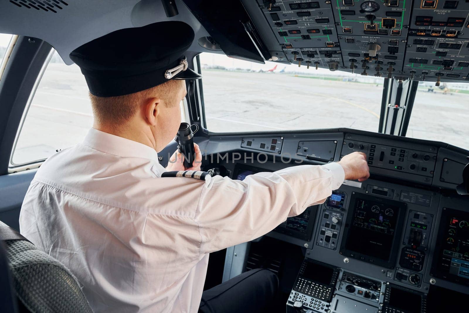 Pilot in formal wear sits in the cockpit and controls airplane by Standret