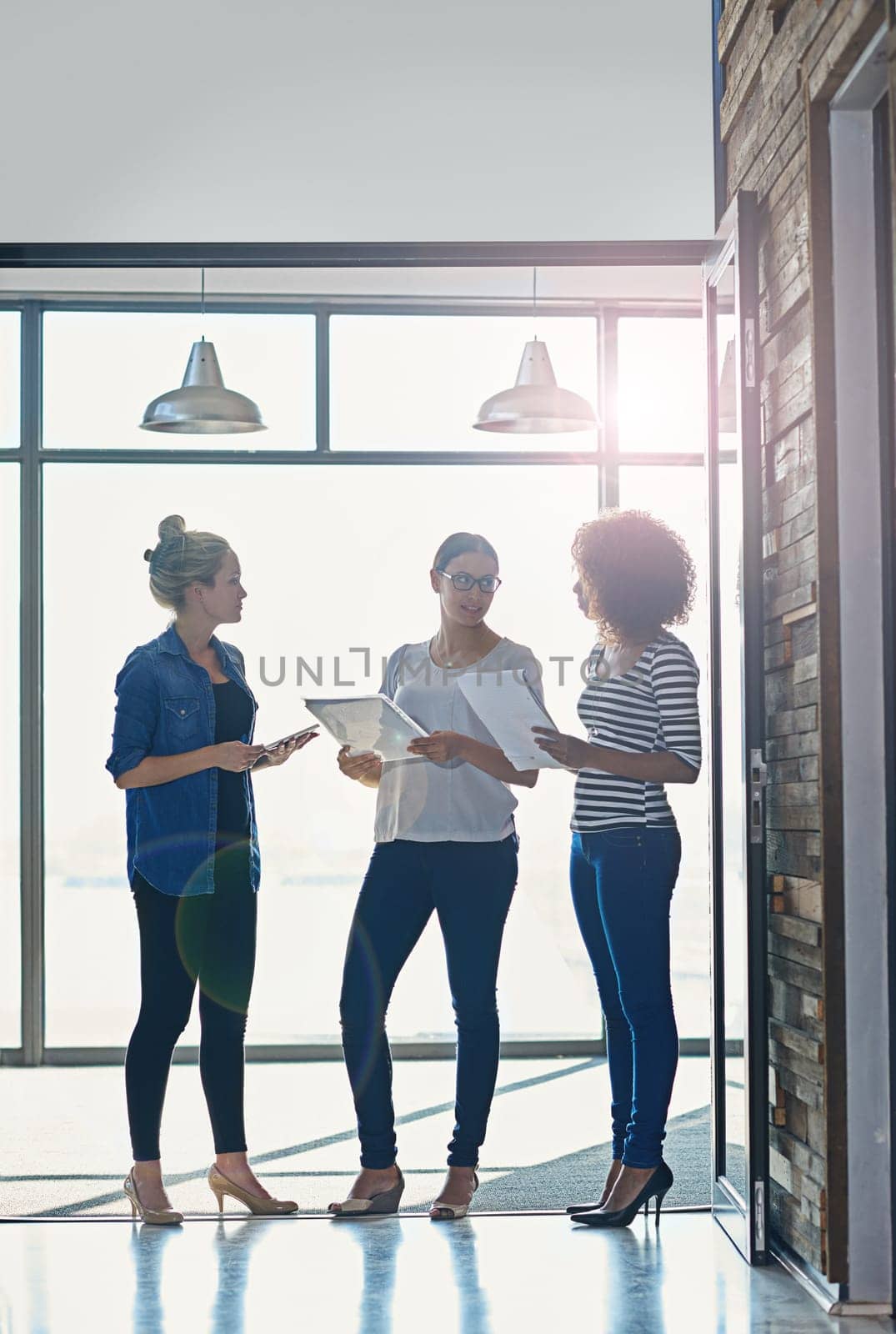 Office discussion on the go. female coworkers talking while standing in front of a window in an office