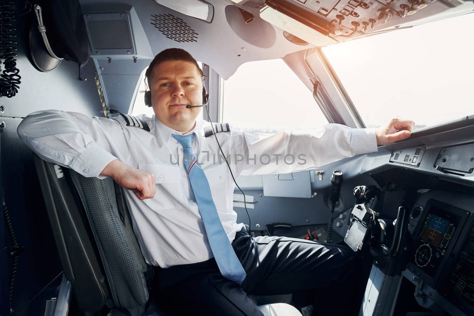 Pilot in formal wear sits in the cockpit and controls airplane by Standret