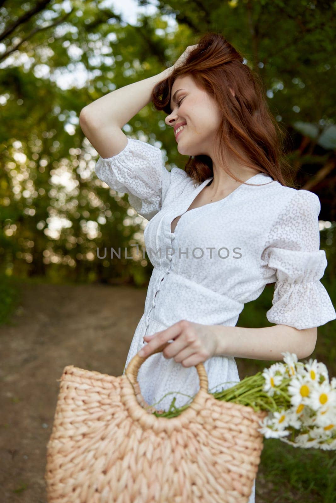 portrait of a beautiful red-haired woman with a wicker basket in her hands, holding her hair with her hand, walks in the park. High quality photo