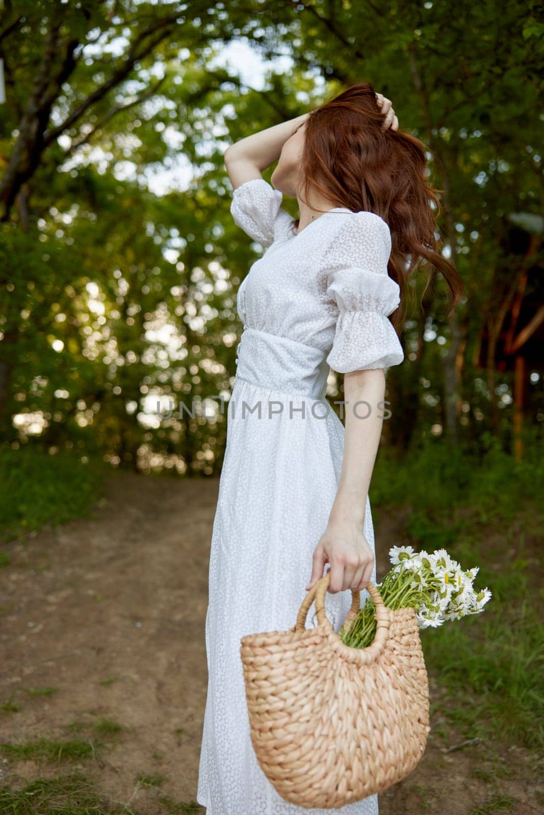 portrait of a beautiful red-haired woman with a wicker basket in her hands, holding her hair with her hand, walks in the park. High quality photo