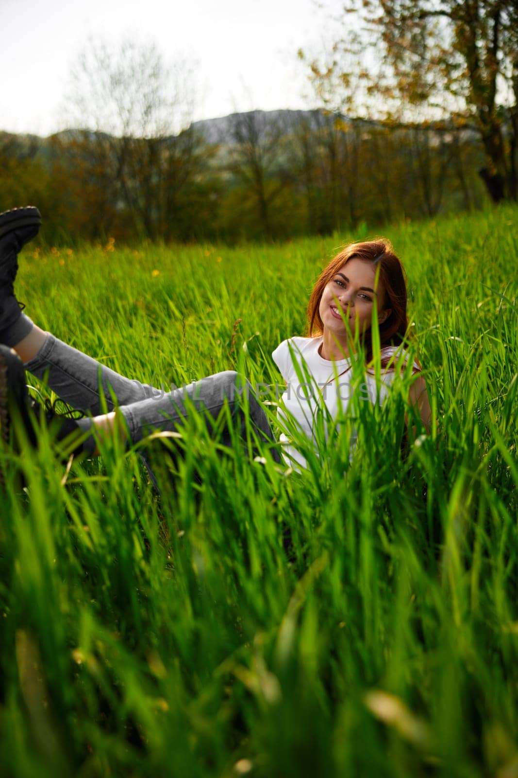 portrait of a joyful cute woman sitting in the grass by Vichizh