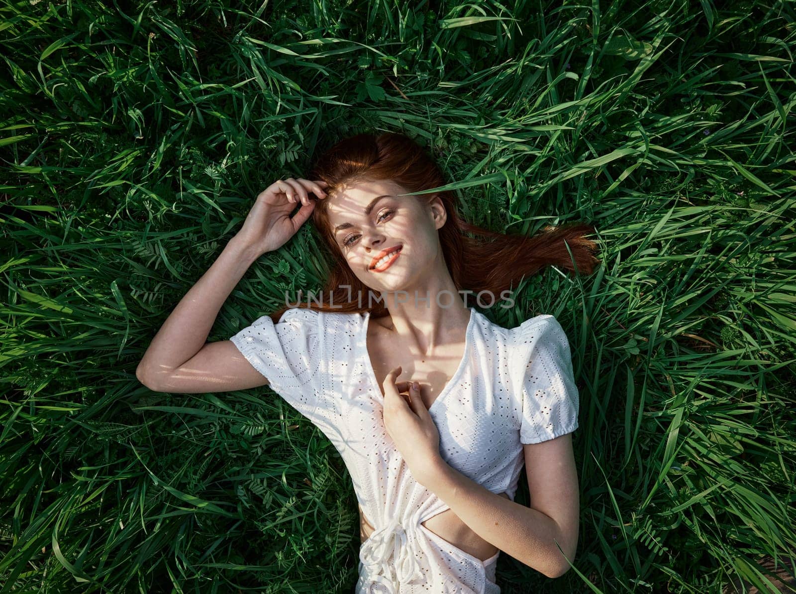 an elegant woman in a light dress lies in the grass and enjoys life by Vichizh