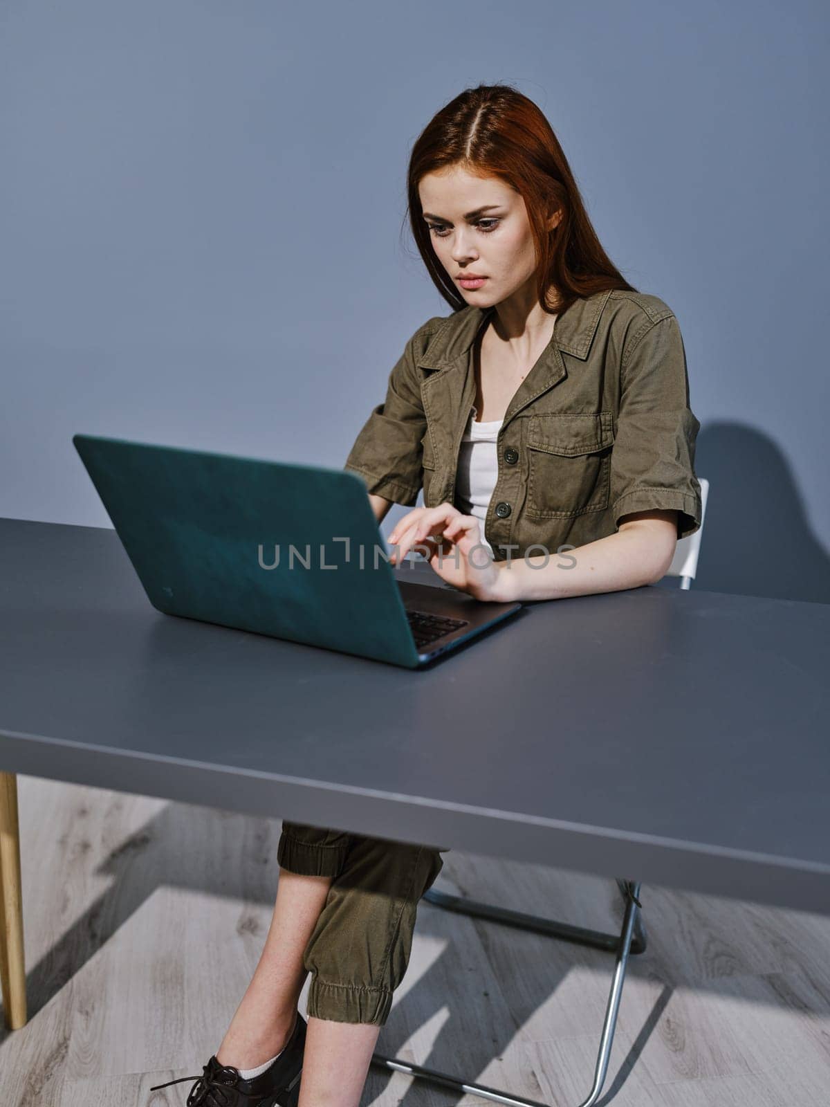 woman working on a laptop while sitting in a room at a table. High quality photo