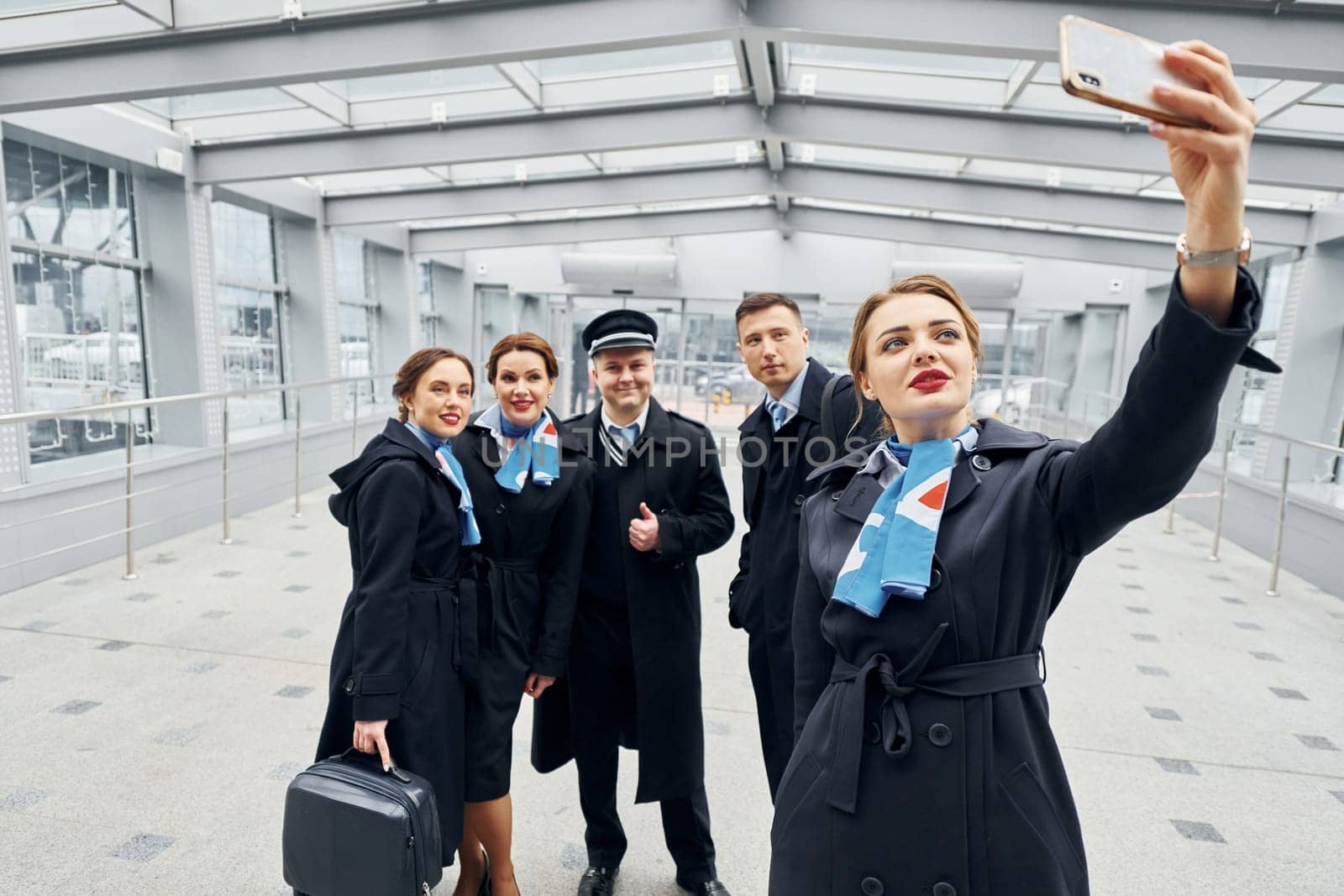Doing selfie. Airplane crew in uniform is going to the work together.