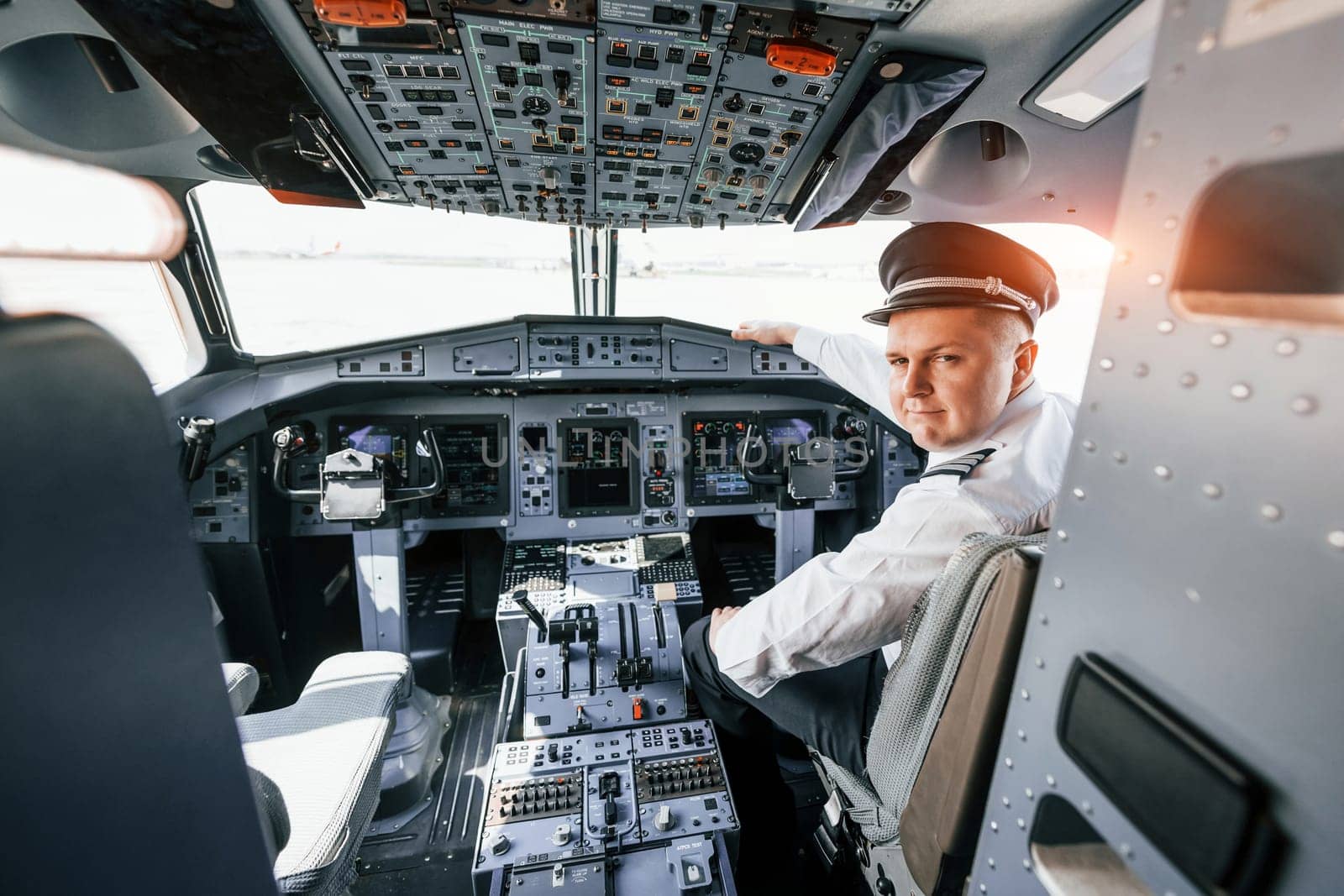 Looks behind. Pilot on the work in the passenger airplane. Preparing for takeoff by Standret