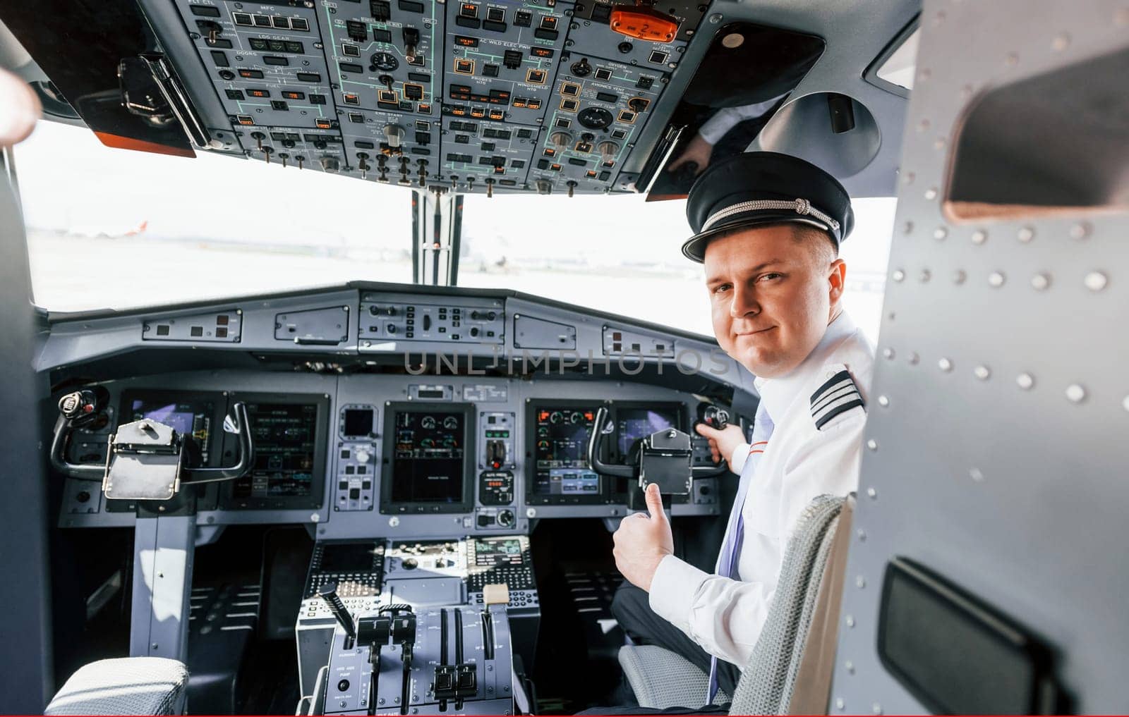 Looks behind. Pilot on the work in the passenger airplane. Preparing for takeoff by Standret