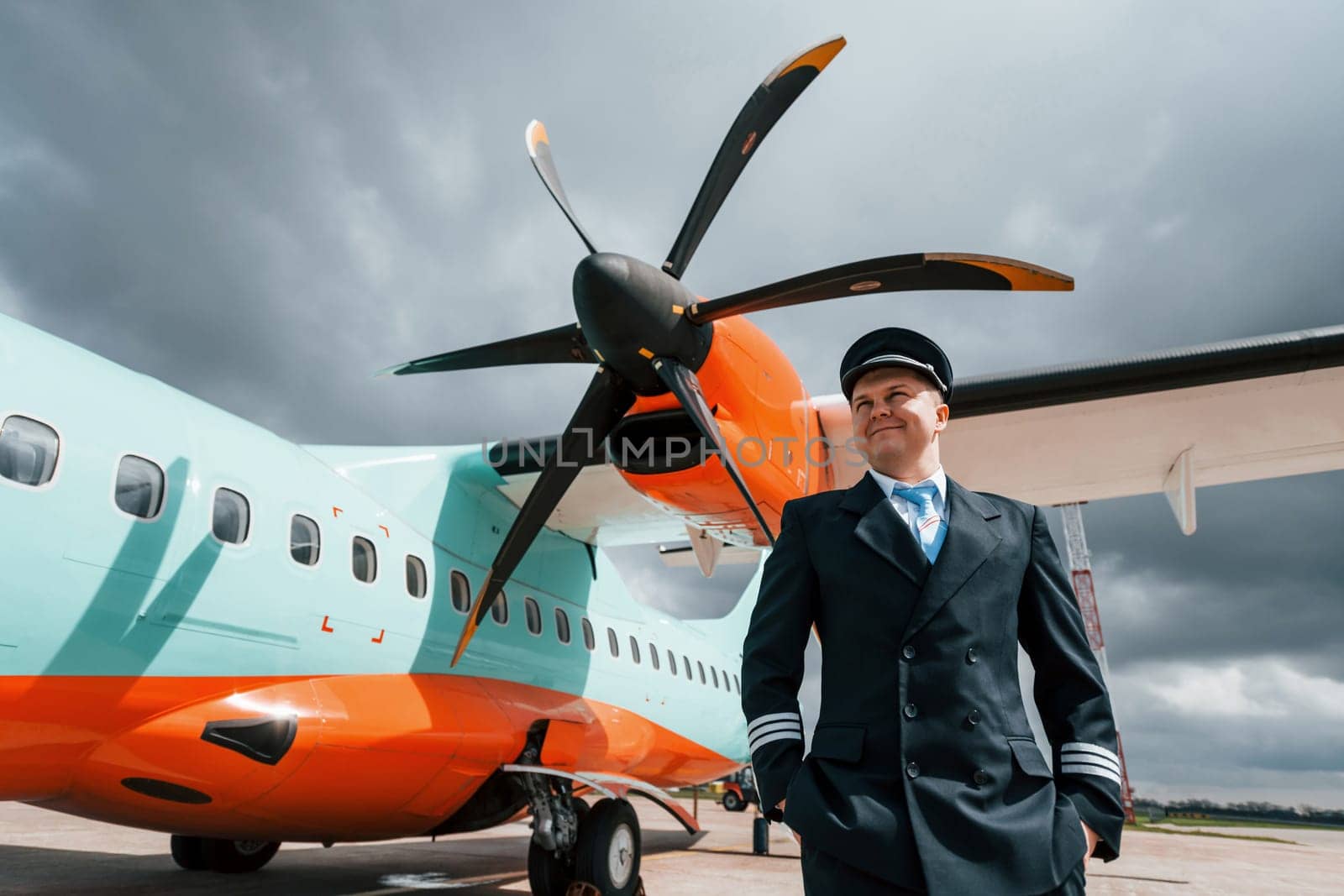 Pilot in uniform standing outdoors near modern airplane by Standret