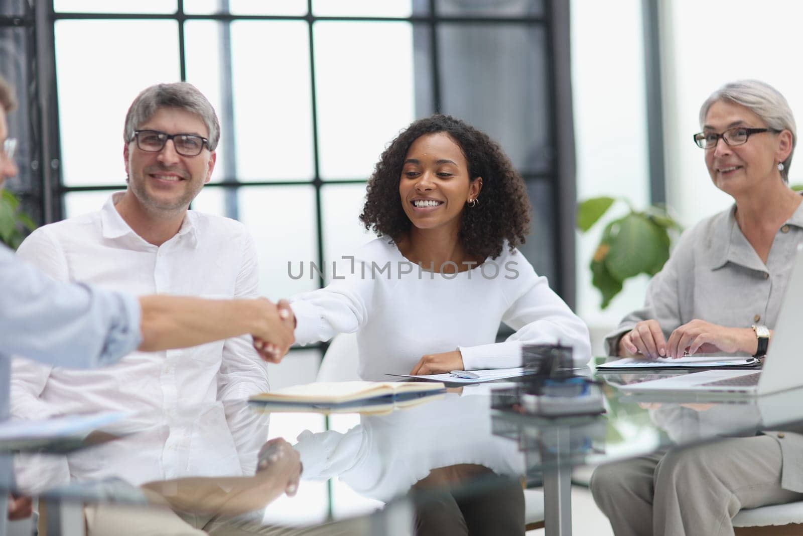 Negotiations in the office. Cheerful businesswoman shaking hands with colleague by Prosto