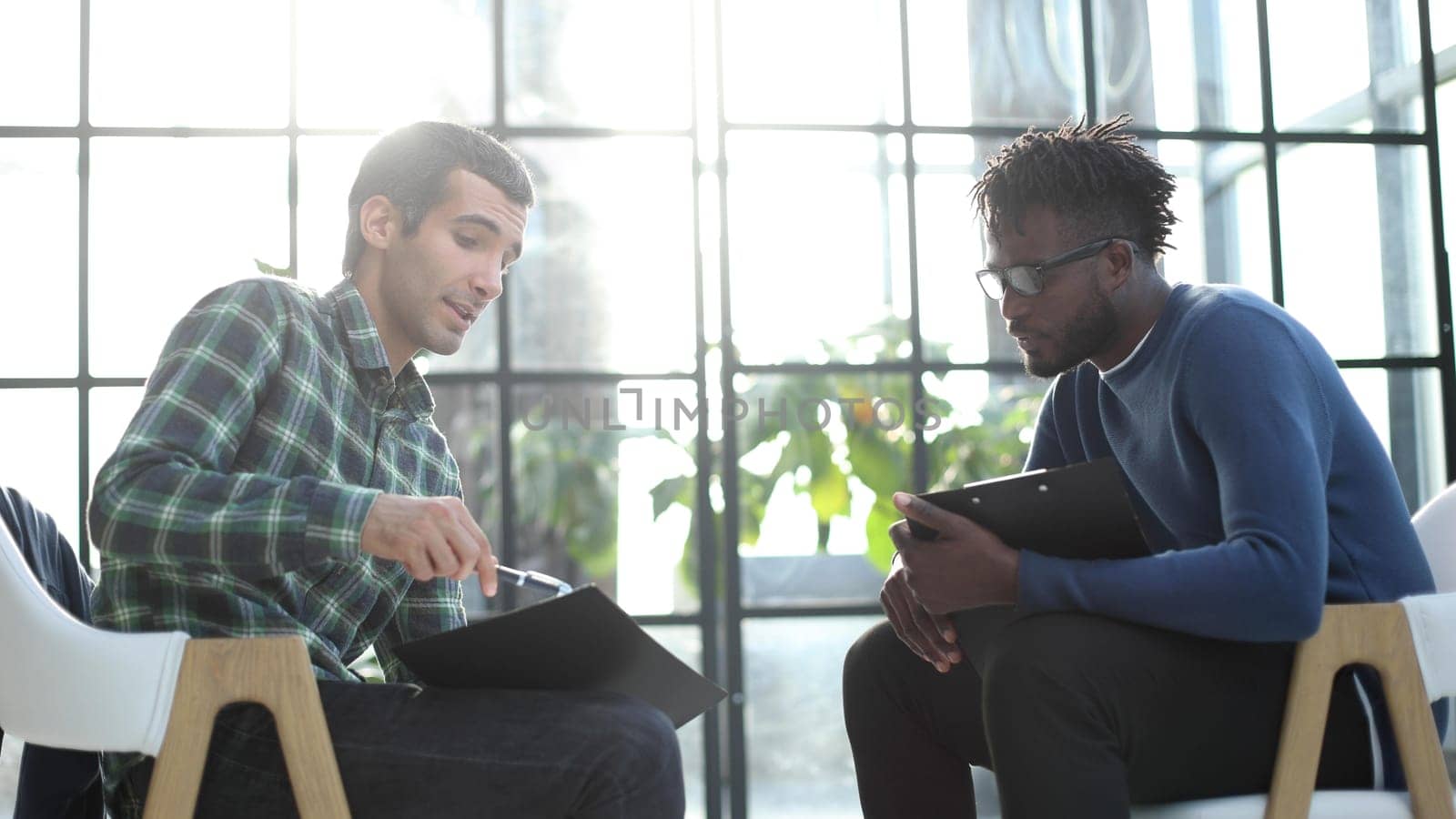 Thoughtful business man in formalwear holding paper while sitting at chair fills out a resume questionnaire in office