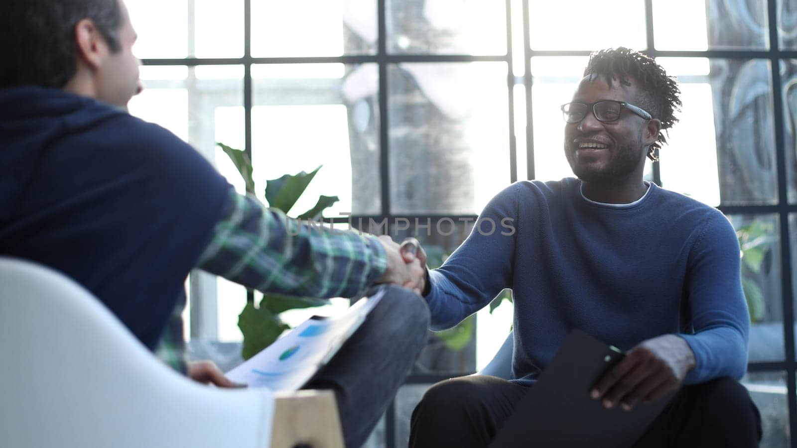 a black man with a folder in his hands shakes hands by Prosto