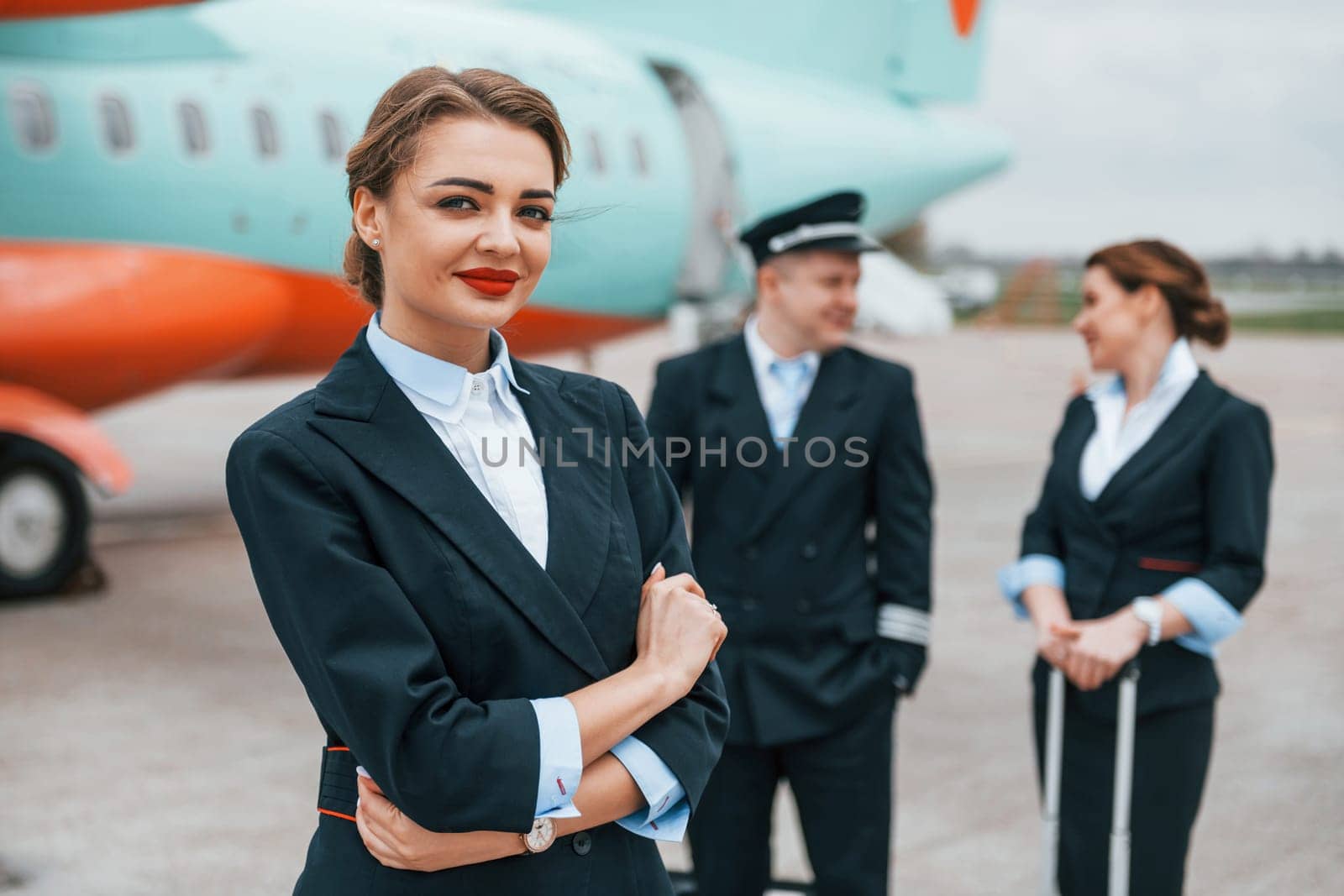 Aircraft crew in work uniform is together outdoors near plane.