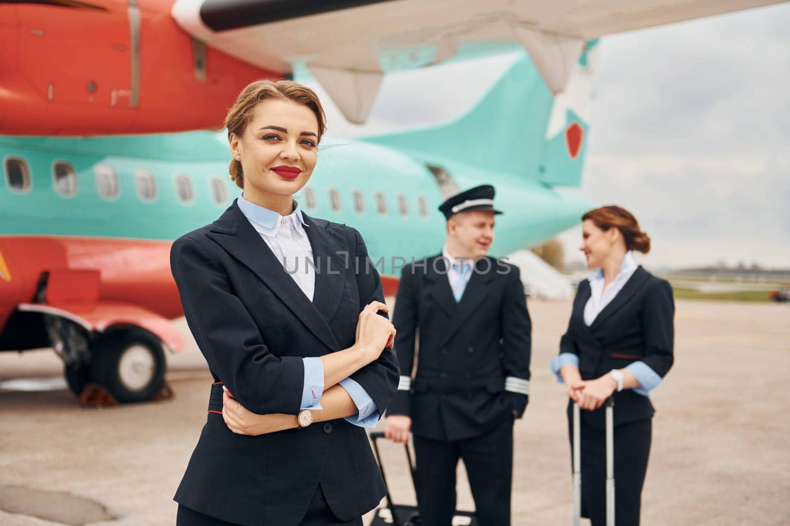 Aircraft crew in work uniform is together outdoors near plane.