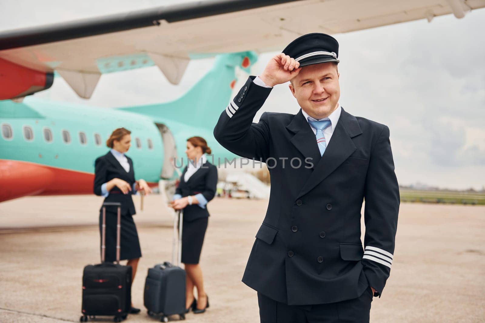 With luggage. Aircraft crew in work uniform is together outdoors near plane by Standret