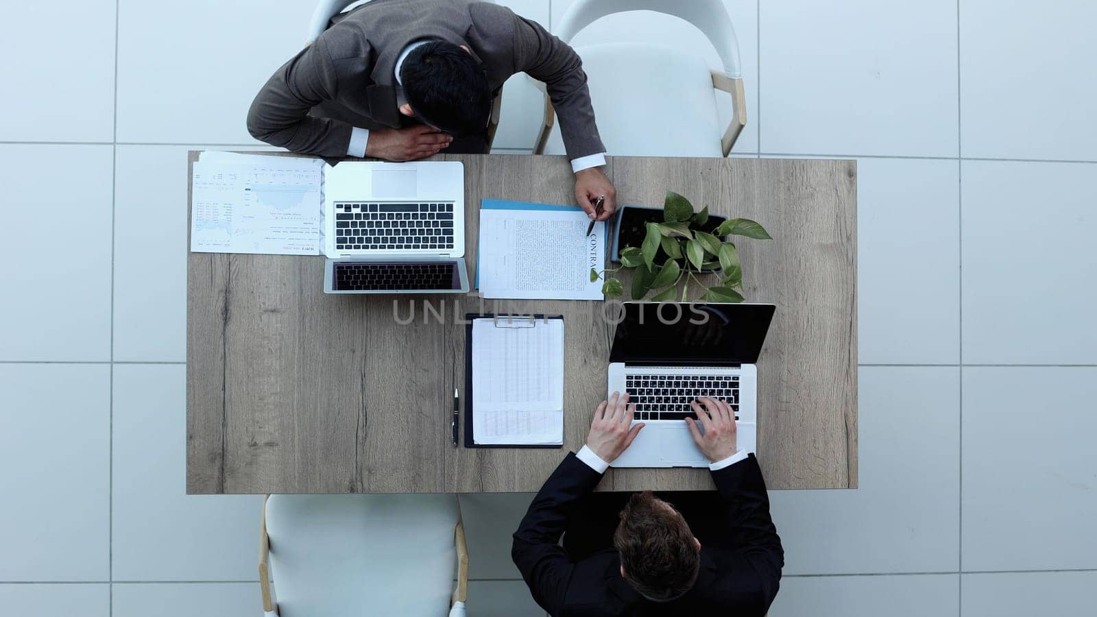 Two successful smiling businessmen are working on a laptop. view from above by Prosto