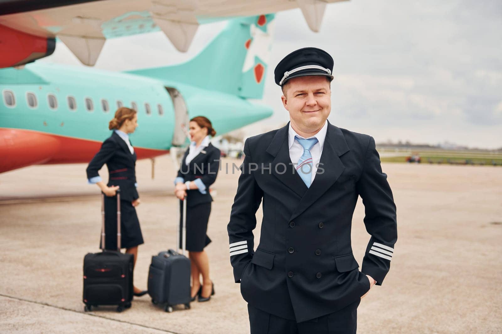 Aircraft crew in work uniform is together outdoors near plane.