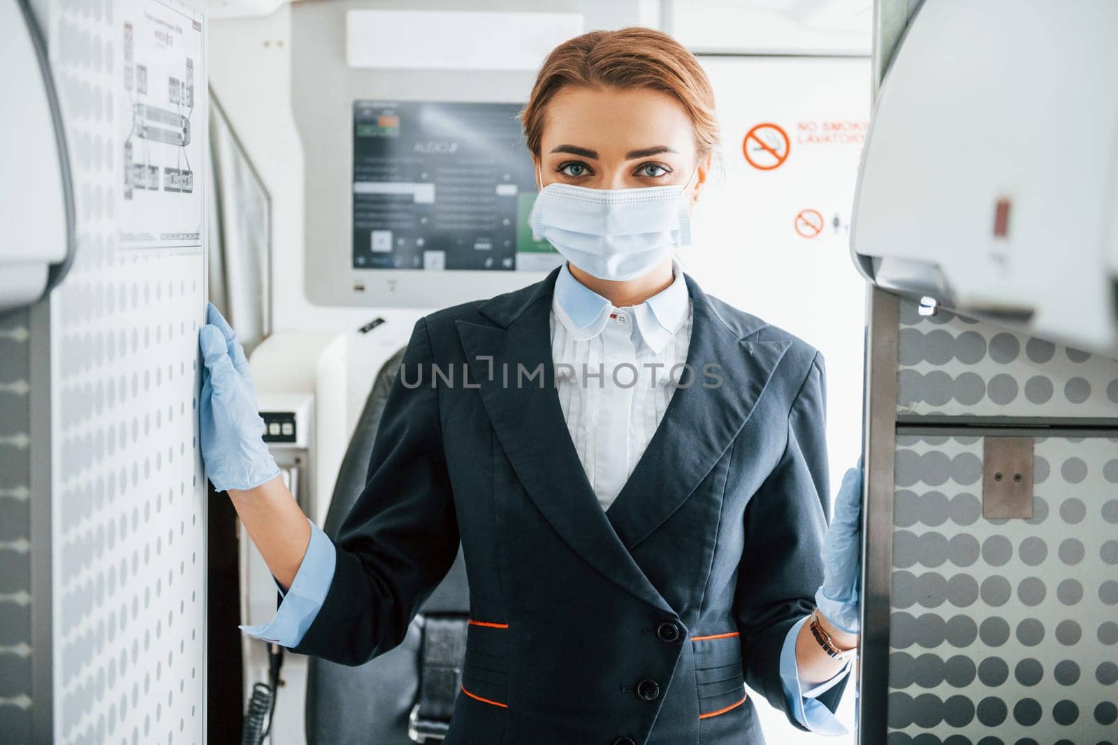 In mask. Young stewardess on the work in the passanger airplane by Standret