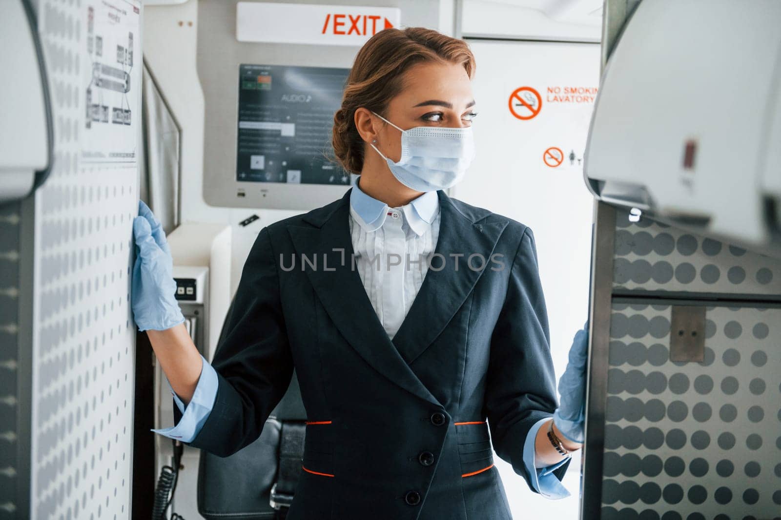 In mask. Young stewardess on the work in the passanger airplane.