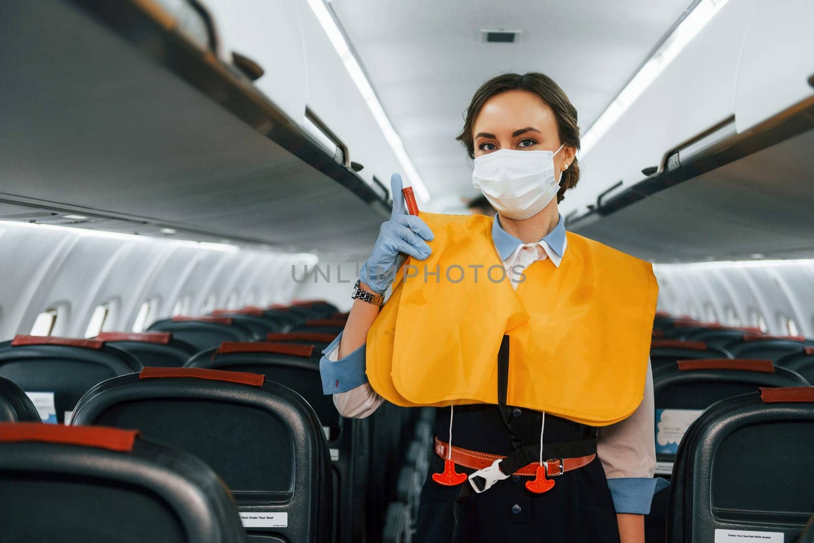 Safety instructions. Young stewardess on the work in the passanger airplane by Standret