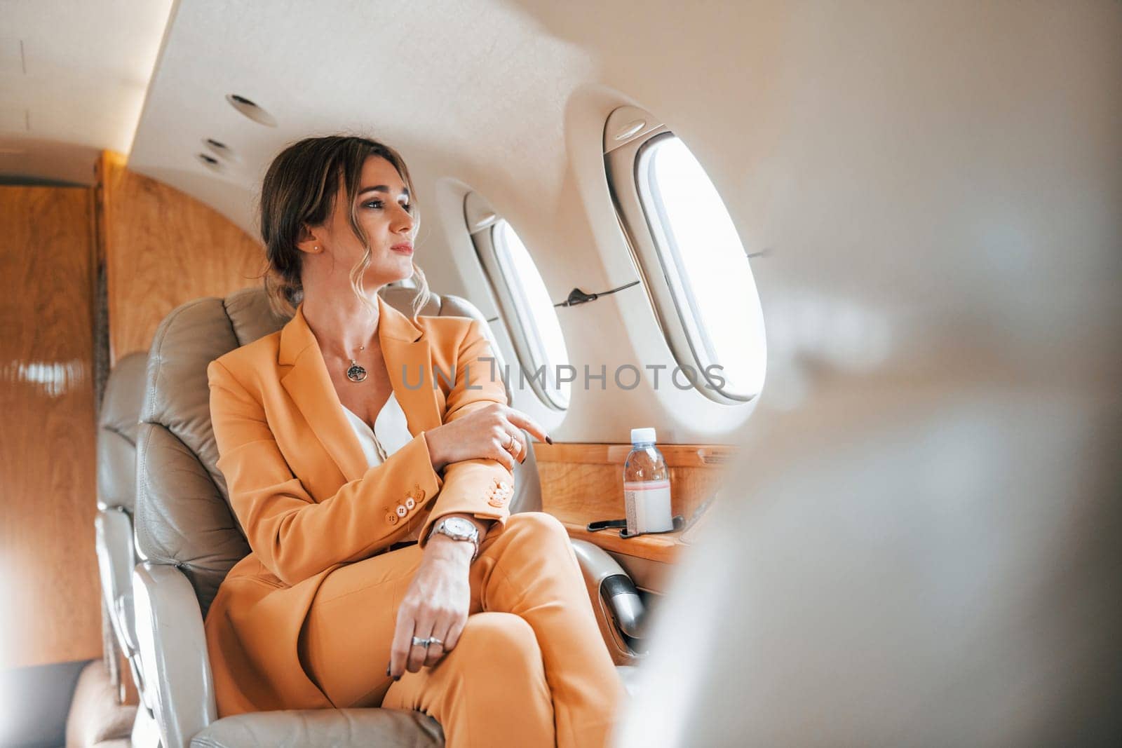 Young passenger woman in yellow clothes is flying in the plane by Standret