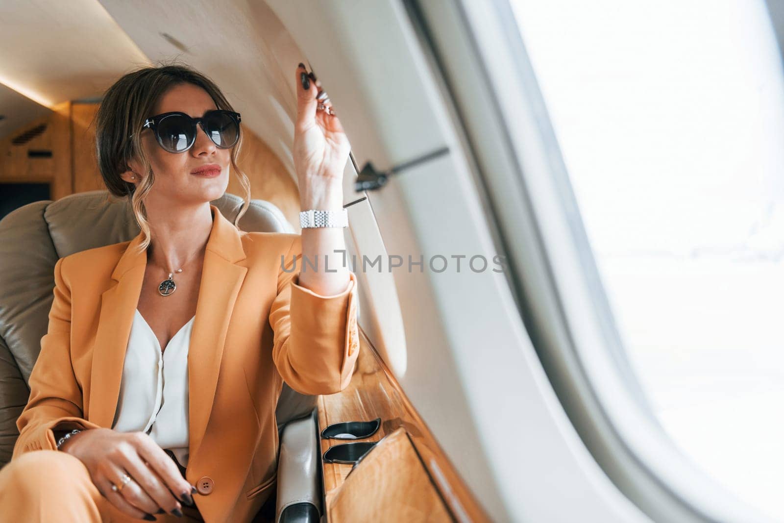 In sunglasses. Young passenger woman in yellow clothes is flying in the plane by Standret